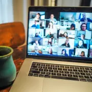 Coffee mug next to a laptop showing a group video call